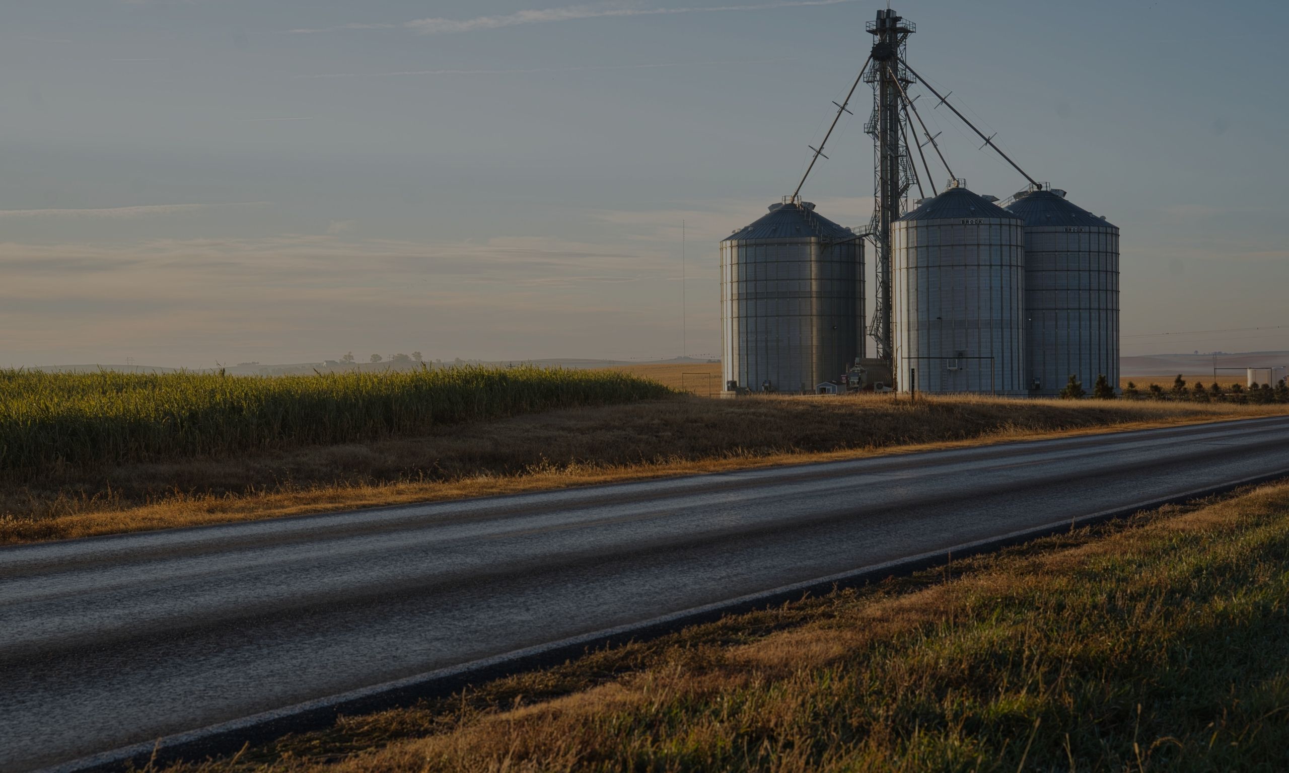 A grain storage system in the middle of a grassy field.