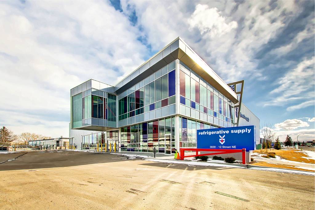 The exterior of the Refrigerative Supply building. Clear, blue, and red windows sparkle in the sunshine.