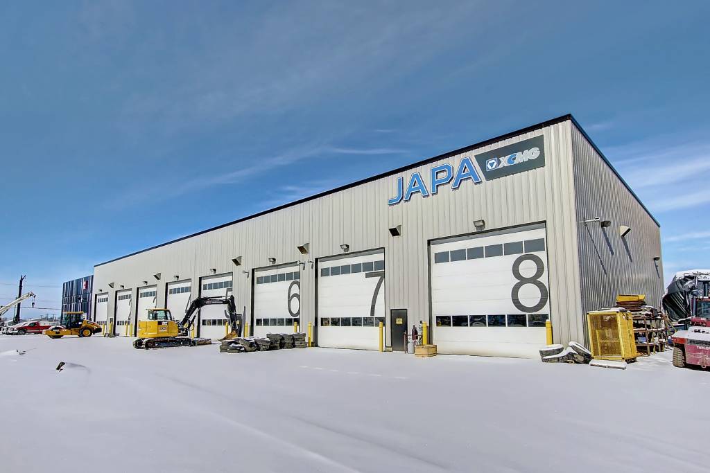 The exterior of JAPA Equipment Rentals and their 8 warehouse bays. The parking lot is covered in snow, and various construction vehicles are parked in the lot.