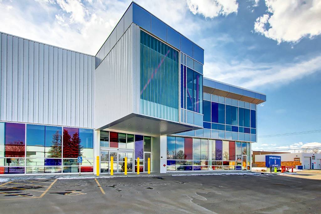 The exterior of Refrigerative Supply. The upper part of the building is silver structured steel, and the bottom half is colored glass: clear, blue, and red.
