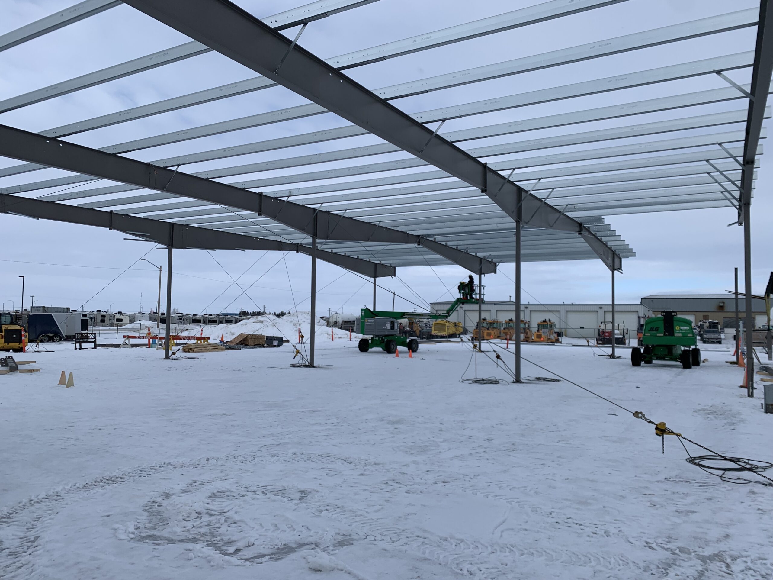 The skeletal structure of a steel building mid-construction. Snow covers the ground.