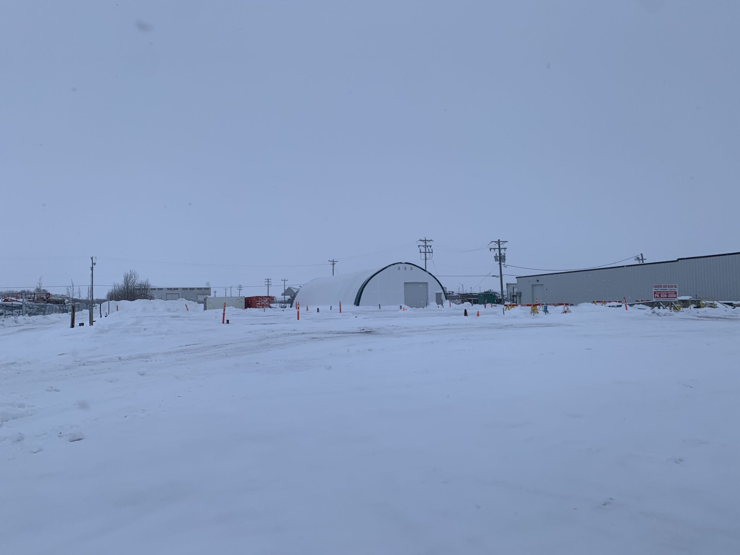 A white quonset in a field covered with snow.