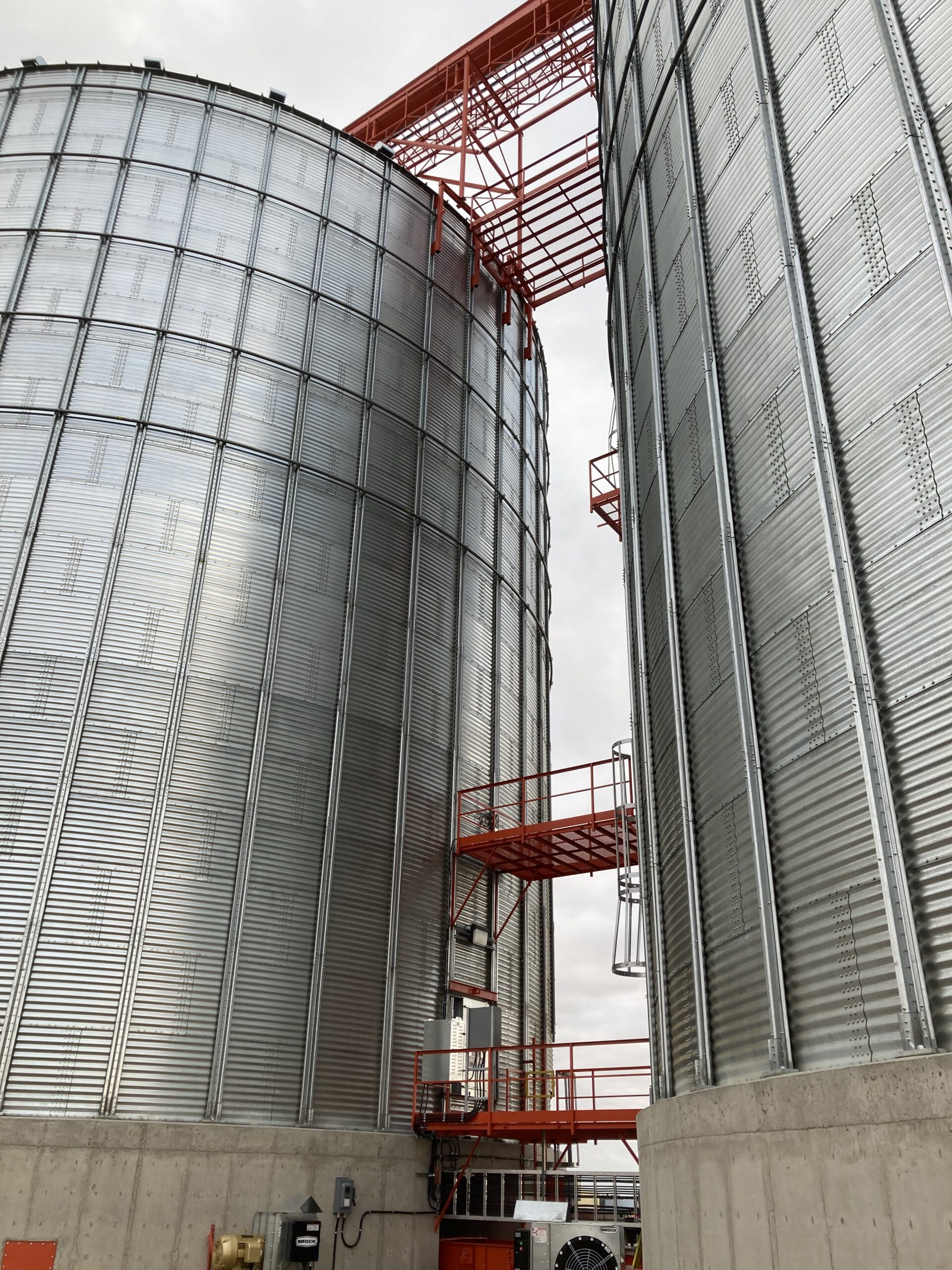 An exterior view of an orange grain elevator between two grain storage systems at Richardson Pioneer