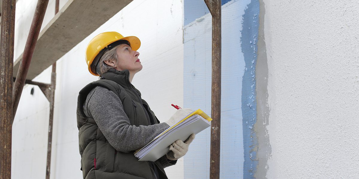 House renovation Construction inspector examine styrofoam insulation of house facade, wall
