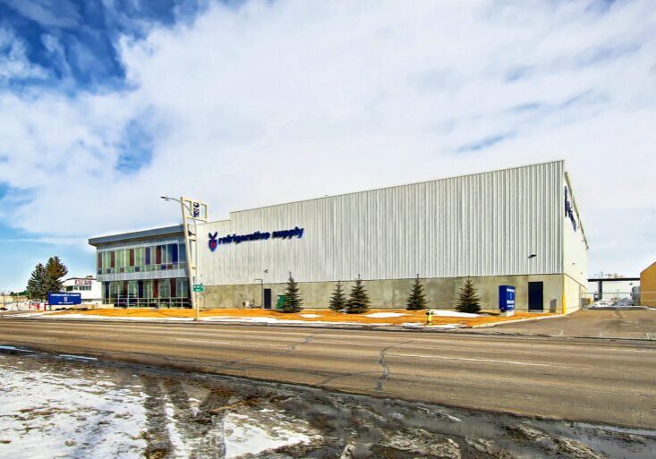 14.Higher_Res.3830_12_St_NE.011471 The exterior of the Refrigerative Supply building. The company sign and logo is on the right hand side of the building. Blue and red windows are on the left side.
